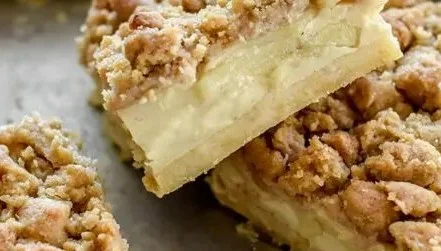 Apfelkuchen vom Blech mit Pudding und knusprigen Streuseln auf einem Teller