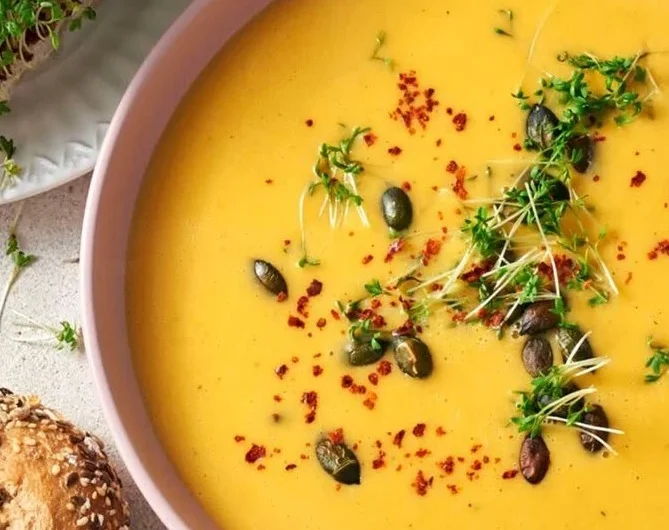 Eine köstliche Schüssel Butternut-Kürbissuppe dekoriert mit frischen Kräutern.