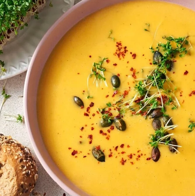 Eine köstliche Schüssel Butternut-Kürbissuppe dekoriert mit frischen Kräutern.
