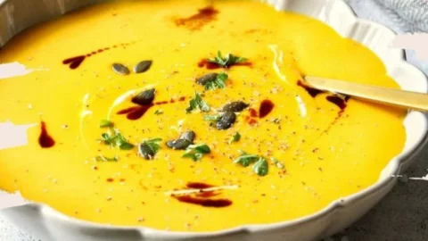 Cremige Kürbissuppe in einer Schüssel, garniert mit Kürbiskernen und Petersilie.