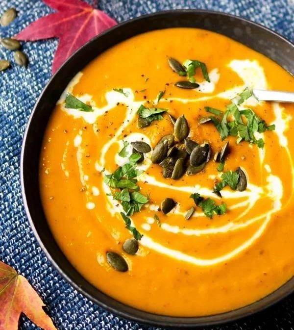 Schüssel mit einfacher Kürbissuppe mit Curry, dekoriert mit frischen Kräutern.