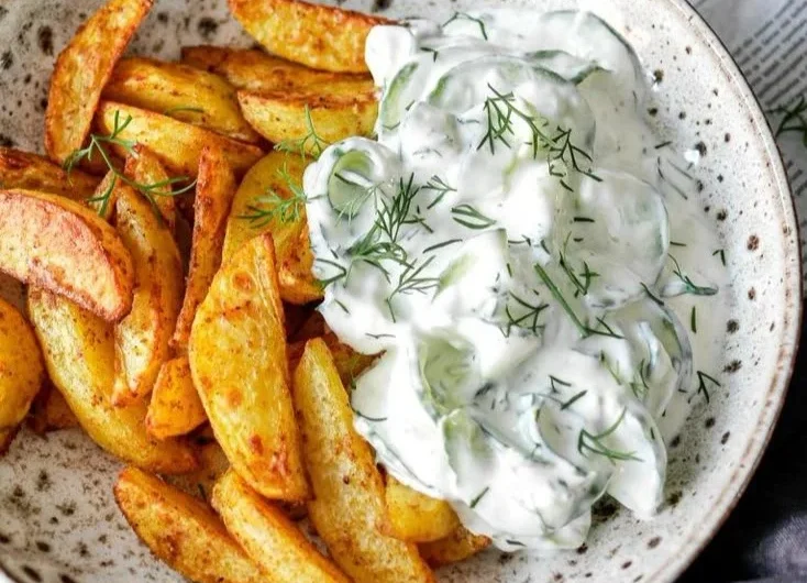 Knusprige Kartoffelspalten serviert mit einem leckeren Gurkendip