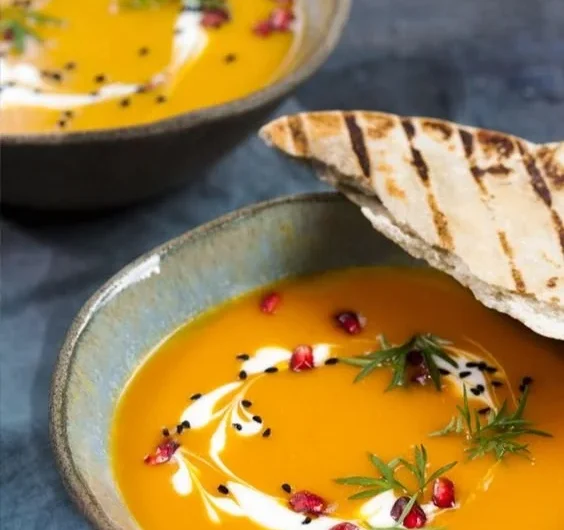 Schüssel mit cremiger Kürbiscremesuppe garniert mit Kürbiskernen und Petersilie