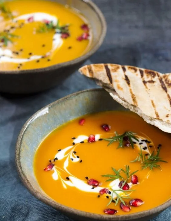Schüssel mit cremiger Kürbiscremesuppe garniert mit Kürbiskernen und Petersilie
