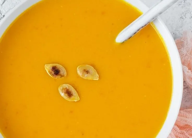 Kürbissuppe aus Hokkaido in einer Schüssel serviert, mit frischen Kräutern garniert.