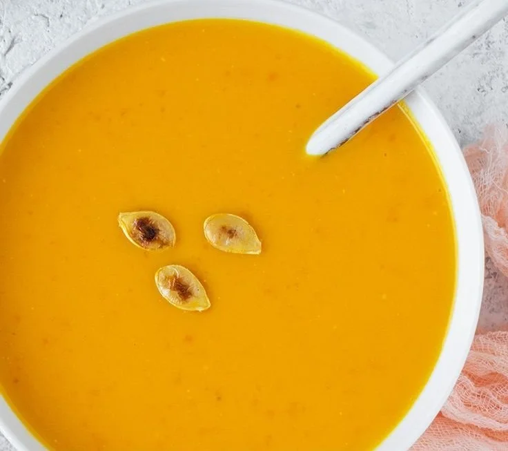 Kürbissuppe aus Hokkaido in einer Schüssel serviert, mit frischen Kräutern garniert.