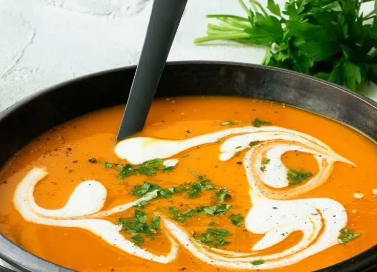 Kürbissuppe in einer Schüssel, garniert mit frischen Kräutern.