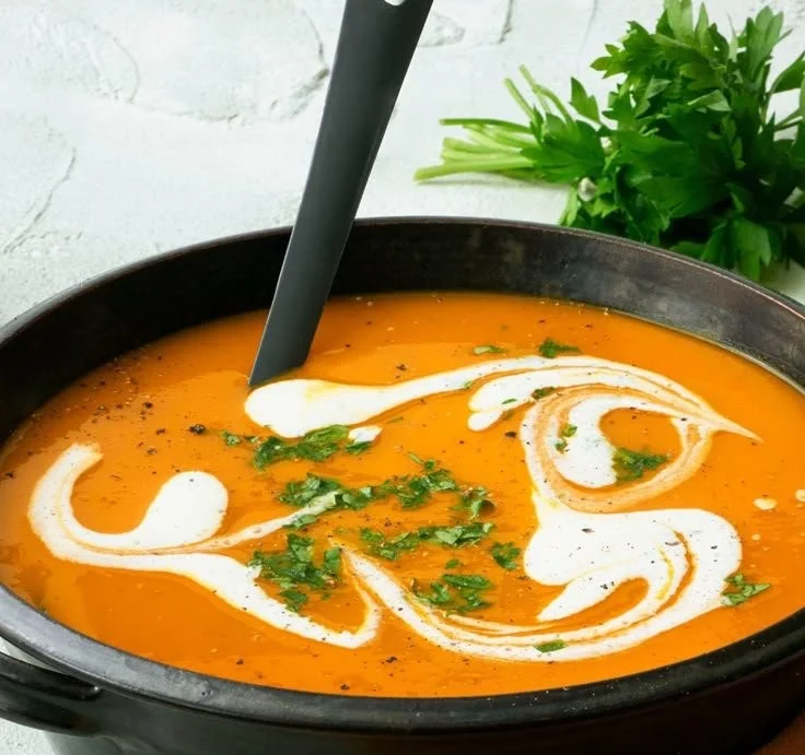 Kürbissuppe in einer Schüssel, garniert mit frischen Kräutern.