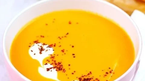 Kürbissuppe mit Kokosmilch in einer Schüssel, garniert mit frischen Kräutern.