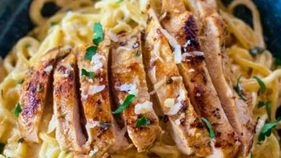 Cremige Pasta Chicken Alfredo auf einem Teller serviert
