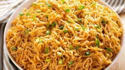 Schüssel mit Sesam-Knoblauch-Ramen-Nudeln, garniert mit frischen Kräutern.