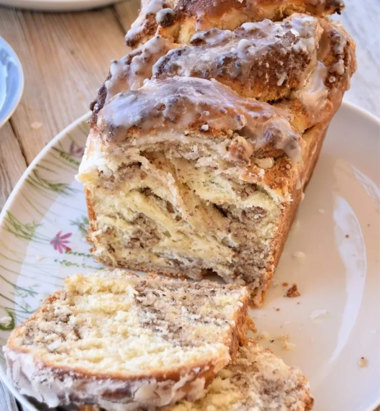 Fluffiger Zopf mit Meringe-Haselnuss-Füllung auf einem Holzbrett.