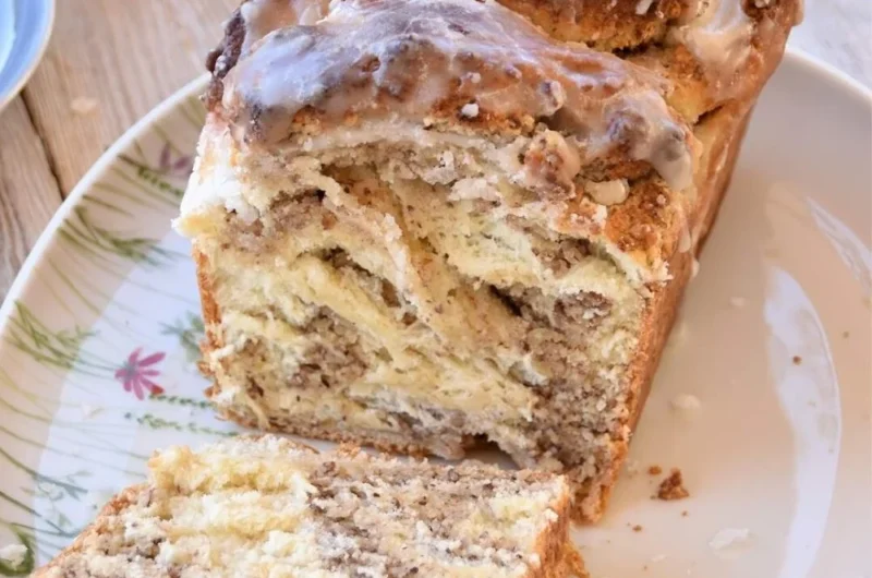 Fluffiger Zopf mit Meringe-Haselnuss-Füllung auf einem Holzbrett.