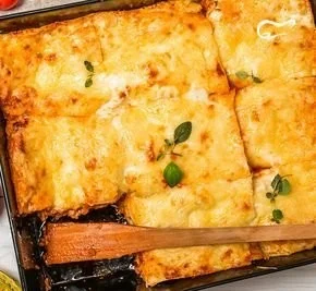Schnelle und cremige Kürbislasagne auf einem Teller, dekoriert mit frischen Kräutern.
