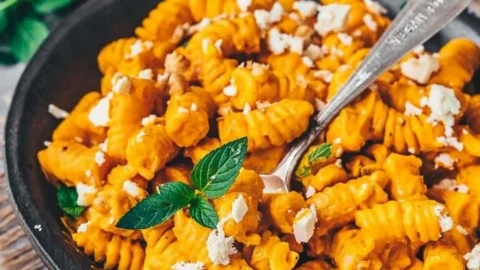 Pasta mit Kürbissauce auf einem Teller serviert, garnierte mit frischen Kräutern