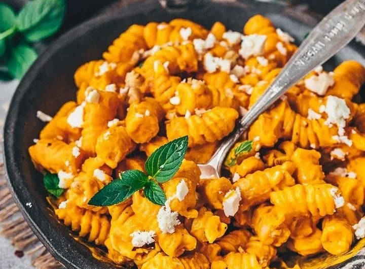 Pasta mit Kürbissauce auf einem Teller serviert, garnierte mit frischen Kräutern