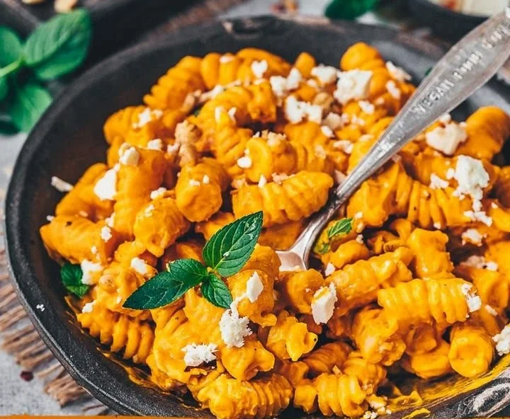 Pasta mit Kürbissauce auf einem Teller serviert, garnierte mit frischen Kräutern
