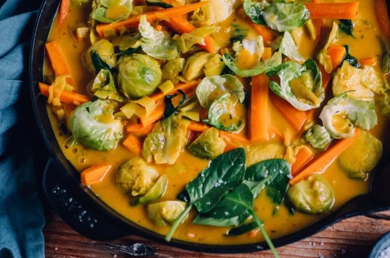 Veganes Rosenkohl-Curry mit Spinat, Karotten und Lauch auf einem Teller