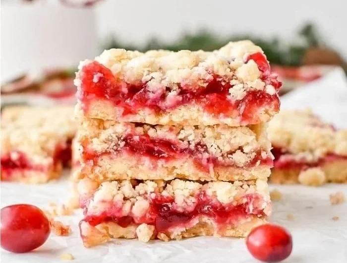 Leckere Cranberry Bars auf einem Teller mit frischen Cranberries und Mandeln.