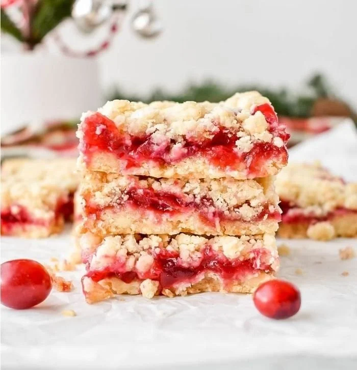 Leckere Cranberry Bars auf einem Teller mit frischen Cranberries und Mandeln.
