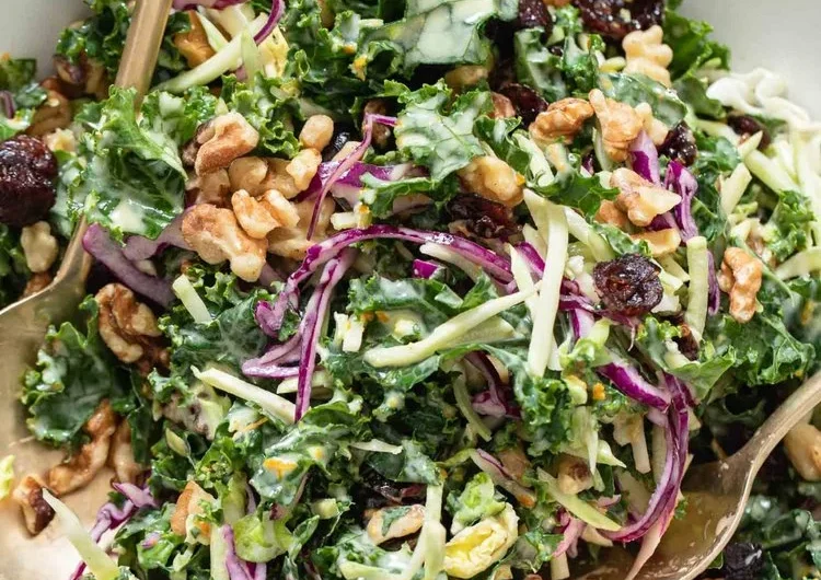 Cranberry-Kale-Salat mit Nüssen und frischem Grünkohl auf einem Teller serviert.