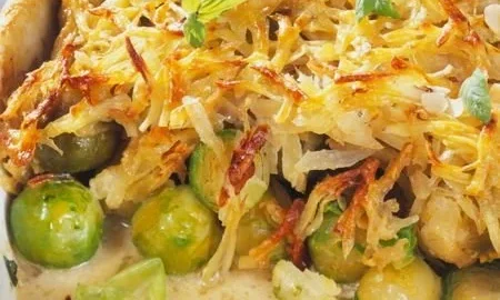 Rosenkohl-Auflauf mit Kartoffelkruste auf einem Teller serviert.