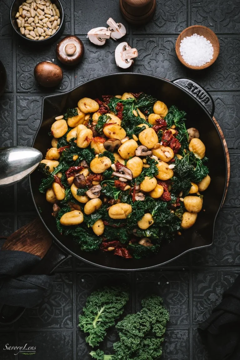 Gnocchi-Grünkohl-Pfanne mit Pilzen und getrockneten Tomaten auf einem Teller serviert.