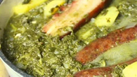 Grünkohl-Eintopf mit Speck und geräucherten Würsten in einer Schüssel.