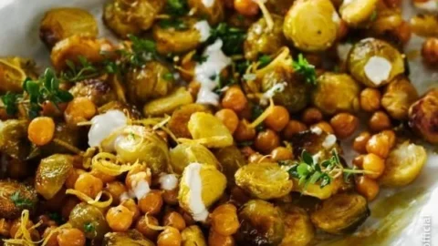 Gerösteter Rosenkohl mit Kichererbsen und Zitronen-Dip auf einem Teller.